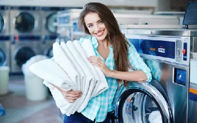 A customer holding folded laundry in a laundromat